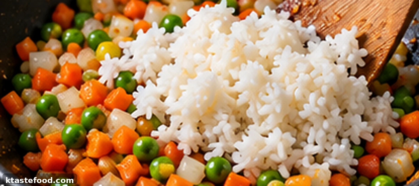 Day-old rice added to vegetables in a pan for Korean shrimp fried rice