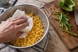 Drained sweet corn being dried beside hand-cut green bell pepper strips