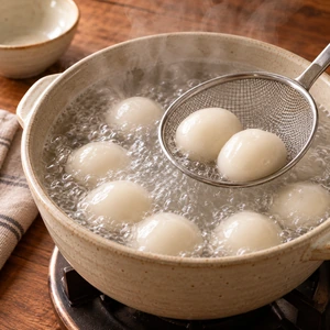 Flattening sweet rice dough placing sweet red bean paste in the center and sealing a gyeongdan rice ball