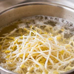 Soybean sprouts added to simmering water with minced garlic