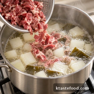 Beef being added to gently simmering Korean radish soup