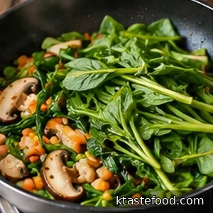 Green water spinach stems and leaves wilting together with mushrooms and carrots in a skillet.