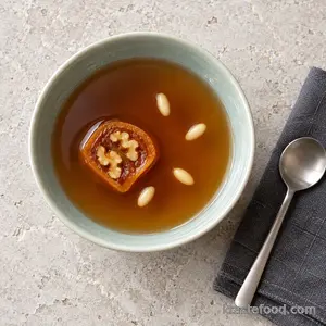 Chilled sujeonggwa served with a persimmon-walnut slice and pine nuts